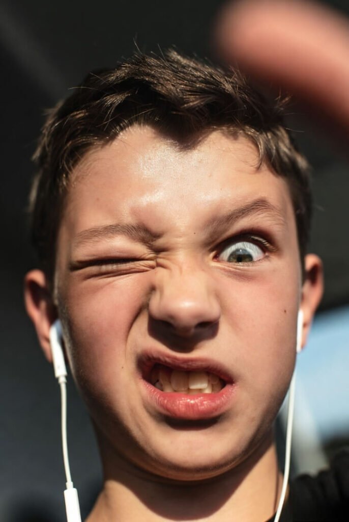 Extreme close-up of a teen's eyes mid-slowest eye-roll ever, one earbud dangling loose, parent's blurry thumb intruding in the corner.