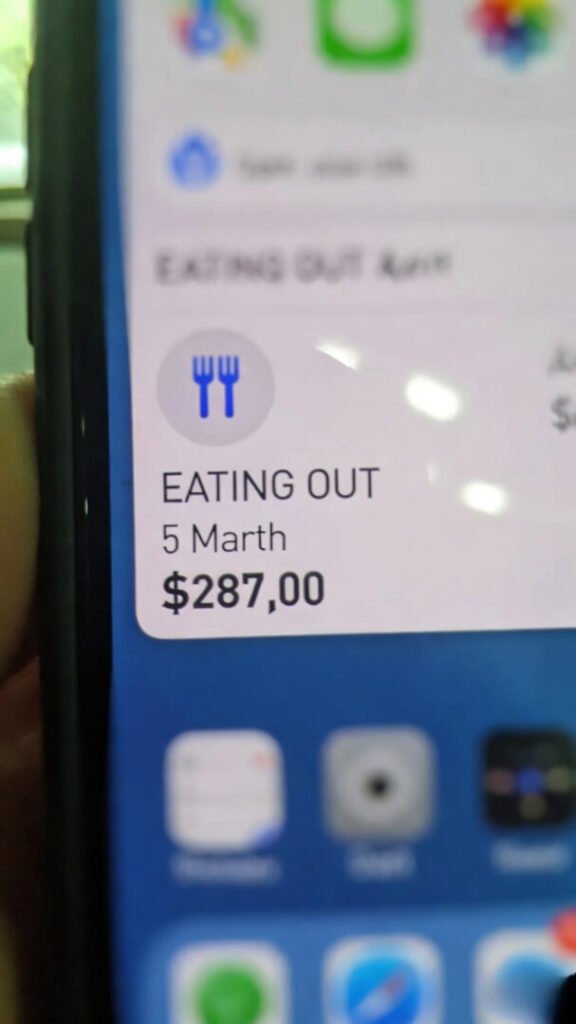 $287 spent on "Eating Out" by March 5th, finger smudge on the edge like it's almost deleted.